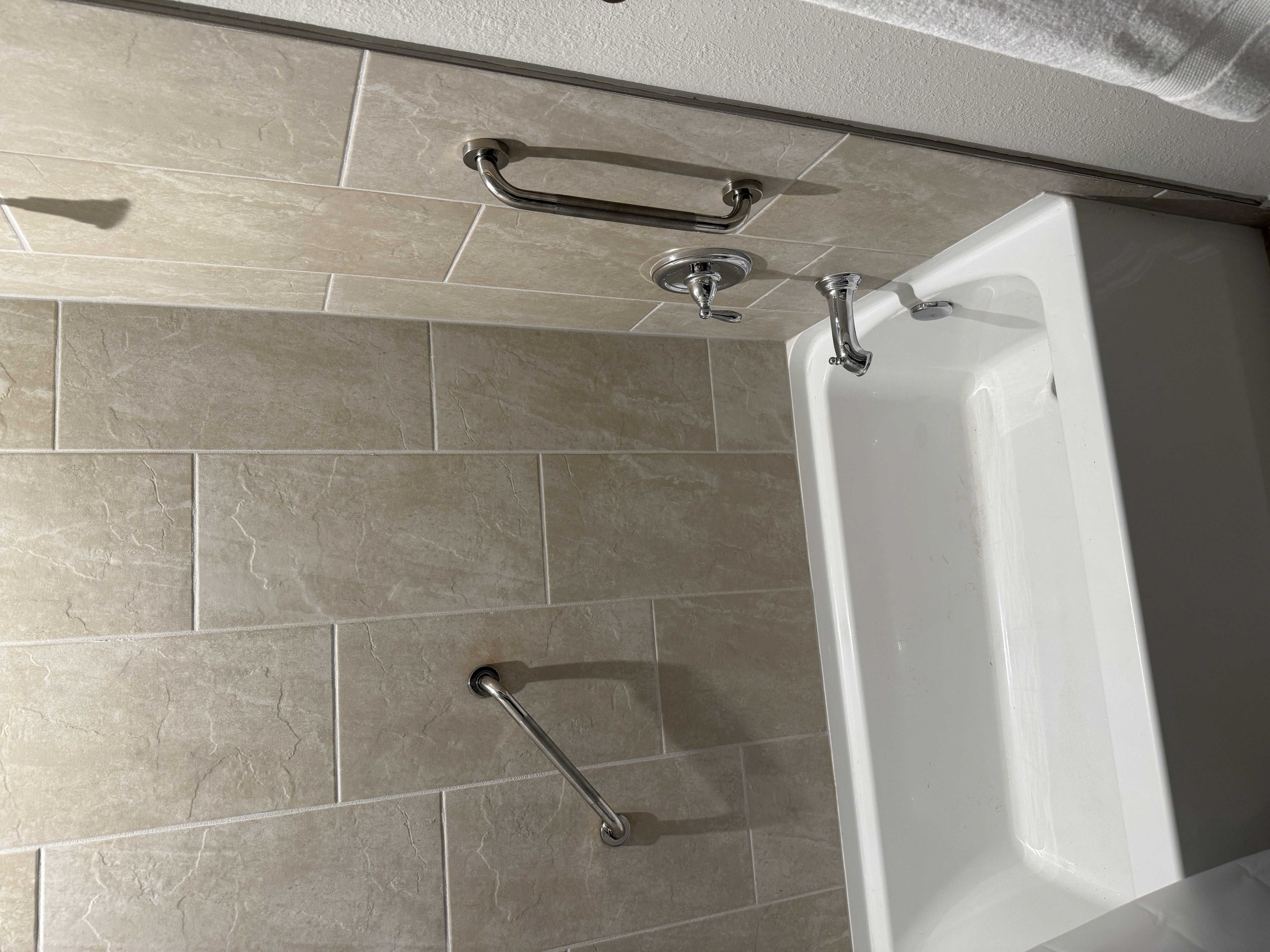 Chrome grab bars installed on tile shower wall next to bathtub — senior safety modification by Rent-A Fella